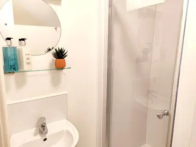a bathroom with a shower and a sink and a mirror at The Paddock in Keswick