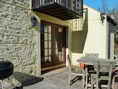 a patio with a table and chairs and a balcony at Arkland Mill in Corsock