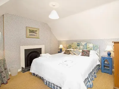 a bedroom with a white bed and a fireplace at Gardener's Cottage-Uxt in Corsock