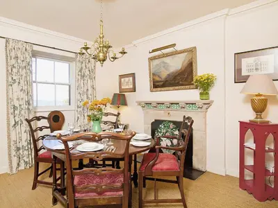 a dining room with a table and a fireplace at Gardener's Cottage-Uxt in Corsock