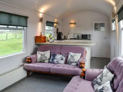 a living room with a purple couch and a kitchen at The Carriage in Bridge of Dee