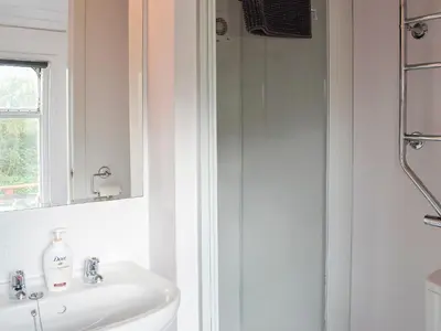 a white bathroom with a sink and a shower at The Carriage in Bridge of Dee