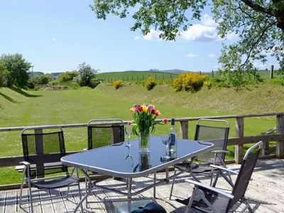a table with a vase of flowers on a deck at The Carriage in Bridge of Dee