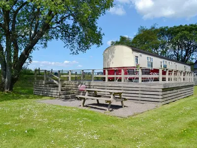 a park bench and a trailer with a house at The Carriage in Bridge of Dee