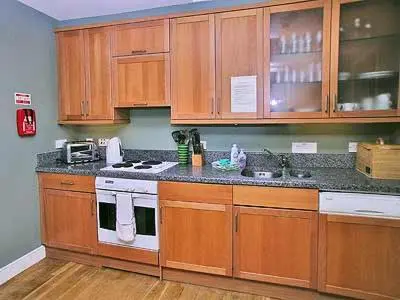 a kitchen with wooden cabinets and a stove top oven at Marwhin Cottage - Swws in Kirkpatrick Durham