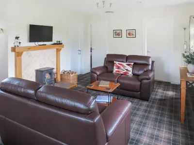 a living room with a leather couch and a table at Swallow Lodge in Carsphairn