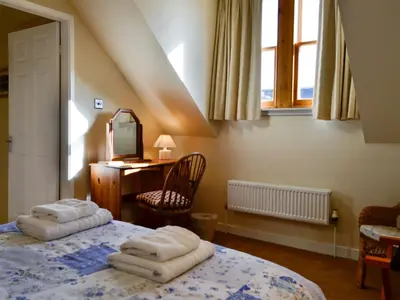 a bedroom with a bed and a desk and a window at Kirsty Cottage in Moffat