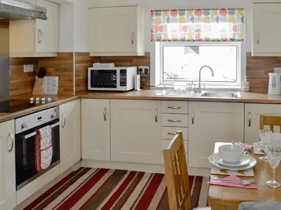 a kitchen with white cabinets and a microwave and a table at Barnhill Bothy in Moffat
