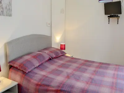 a bedroom with a bed with a plaid blanket at Barnhill Bothy in Moffat