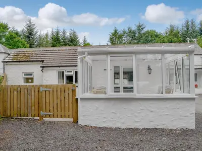 a white cottage with a wooden fence at Barnhill Bothy in Moffat