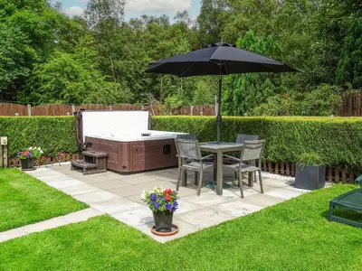 a table and chairs under an umbrella in a yard at Blaeberry Cottage - 28061 in Dinwoodie Mains