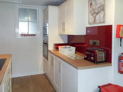 a kitchen with white cabinets and a red appliance at Blaeberry Cottage - 28061 in Dinwoodie Mains