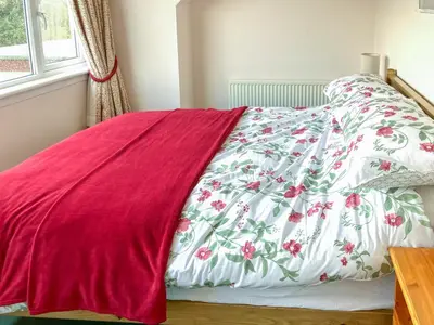 a bed with a red and white blanket on it at Mountain Cross in Gatehouse of Fleet