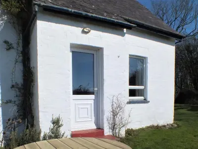 a white house with a door and a window at Olafs Cottage in Garlieston