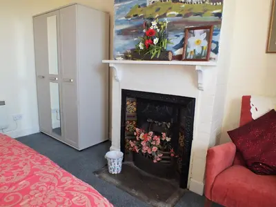 a living room with a fireplace and a red chair at Olafs Cottage in Garlieston