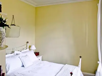 a bedroom with a white bed and a yellow wall at The Cottage in Garlieston