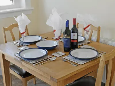 a wooden table with plates and wine bottles and glasses at Winloma in Port William