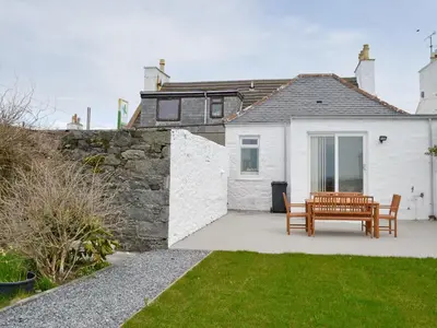 a white house with a wooden bench in the yard at Sea-Esta - 28175 in Port William