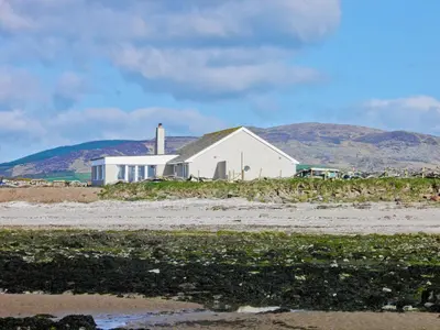 a white house with a mountain in the background at Driftwood in Mainsriddle