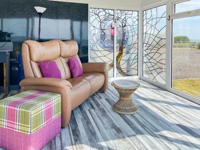 a living room with a leather chair and a table at Driftwood in Mainsriddle