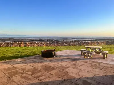 a picnic table and a bench and a trash can at Driftwood in Mainsriddle