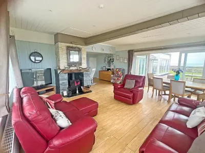 a living room with a red leather couch and chairs at Driftwood in Mainsriddle