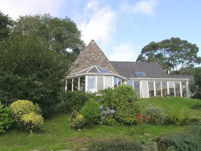 a house with a conservatory on a hill with plants at Holly Cottage - 28140 in Boreland of Colvend