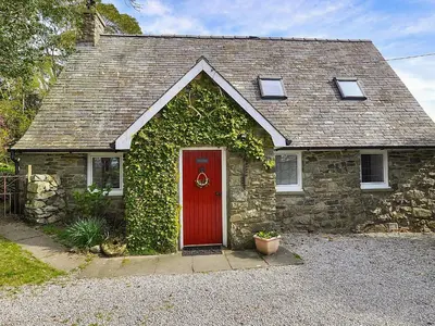 a stone house with a red door and ivy at Holly Cottage - 28140 in Boreland of Colvend
