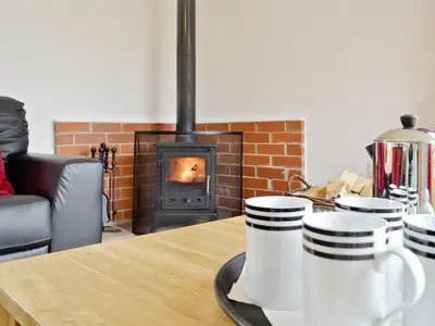 a table with three coffee cups on a table with a fireplace at Rose Cottage - 28176 in Fairgirth