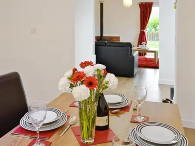 a table with plates and a vase of flowers on it at Rose Cottage - 28176 in Fairgirth