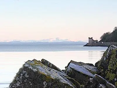 a group of rocks in the water with a castle in the background at Myrtle Cottage - 28177 in Fairgirth