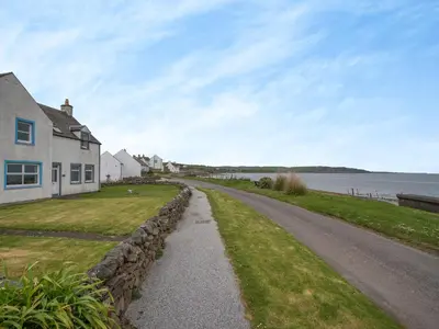 a road next to a house and a body of water at Jura in Drummore