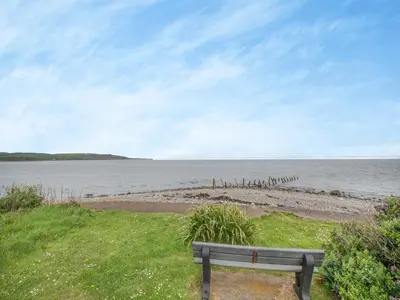 a bench sitting on the grass near a body of water at Jura in Drummore