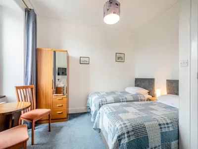 a bedroom with two beds and a table and a chair at Braefield in Portpatrick