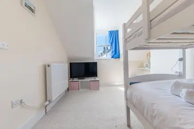 a white bedroom with a bunk bed and a television at Hazelgrove, Ratcliffe Place, Keswick in Keswick