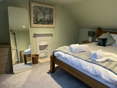 a bedroom with a bed with a fireplace and a mirror at Apple Cottage in Wigtown