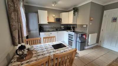 a kitchen with a table and chairs and a kitchen with white cabinets at The Chalets in Eskdale