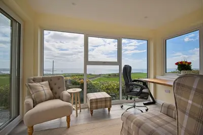 a home office with a desk and chairs and windows at High Auchenlarie Cottage in Gatehouse of Fleet