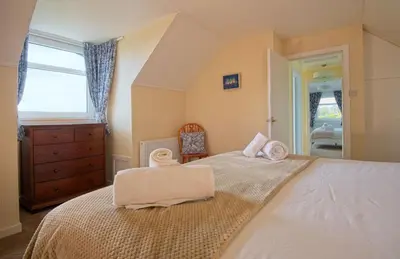 a bedroom with a bed with two towels on it at High Auchenlarie Cottage in Gatehouse of Fleet
