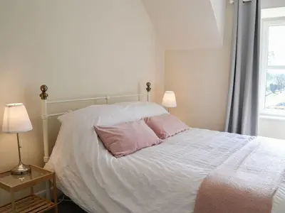 a bedroom with a white bed with two pink pillows at Blackloch in Gatehouse of Fleet
