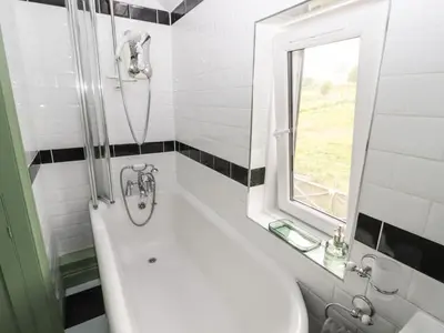 a bathroom with a tub and a sink and a window at Beech Croft in Keswick