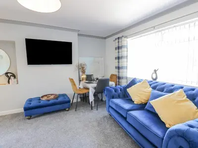 a living room with a blue couch and a table at 22 Turnberry Road in Girvan
