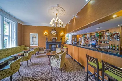 a restaurant with a bar and tables and chairs at Hunday Manor Country House Hotel in Workington