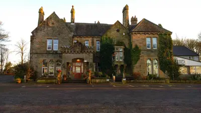 an old brick house with people standing in front of it at Hunday Manor Country House Hotel in Workington