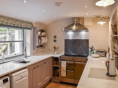 a kitchen with a stove top oven next to a window at Earsdon Cottage in Ireby