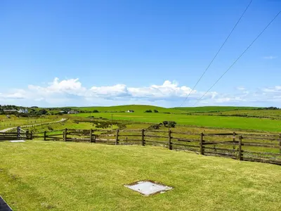 a field with a fence and green grass at Little Glengyre Farm in Kirkcolm