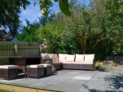 a couch and a bench in a garden at Southways Cottage in Cumwhinton