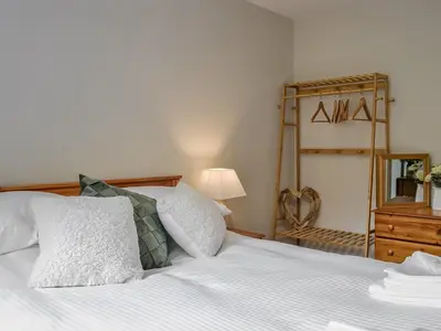 a bed with white sheets and pillows in a bedroom at Southways Cottage in Cumwhinton