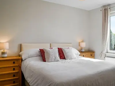 a bedroom with a white bed with two lamps and a window at Southways Cottage in Cumwhinton