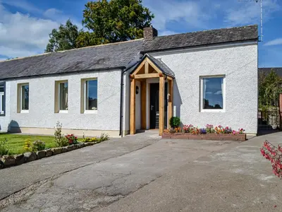 a white brick house with a garage at Southways Cottage in Cumwhinton
